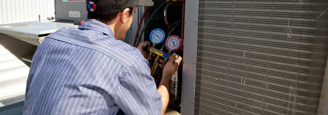 HVAC technician servicing a condenser unit in Walkertown
